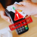 A fake credit card tapped in a machine, depicting a merchant fraud in action