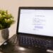 A laptop on a desk showing a simulated phishing email notification about a locked credit card, used as a visual example of phishing threats and the need for effective merchant fraud monitoring systems.