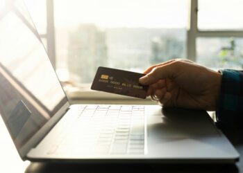 A man holding a credit card as he tries to commit fraud to a high-risk merchant account