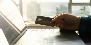 A man holding a credit card as he tries to commit fraud to a high-risk merchant account