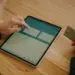 Person entering credit card details on a tablet to complete an online money transfer, illustrating the card-not-present transactions that make eCommerce fraud prevention essential for online merchants.