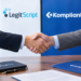 Stock photo of two businesspeople shaking hands over a desk, with LegitScript and Kompliant branded folders, a pen, and a signed document on the table, and company logo banners in the background, symbolizing a partnership between the two compliance companies.