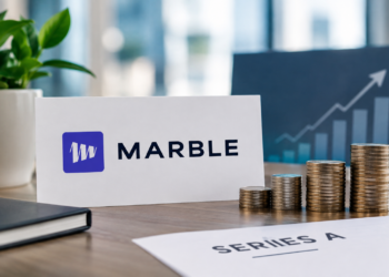 Marble logo sign beside a placard reading 'Series A €6.5M ($7.3M)' with stacks of gold coins on an office desk.