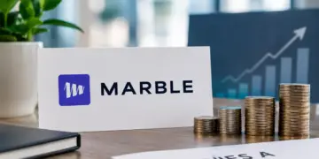 Marble logo sign beside a placard reading 'Series A €6.5M ($7.3M)' with stacks of gold coins on an office desk.