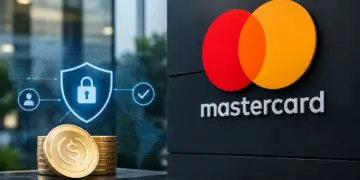 Stock photo of gold coins stamped with a dollar sign beside a digital security shield icon with a padlock, displayed near a large Mastercard logo on a dark wall, symbolizing secure digital payments.