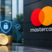 Stock photo of gold coins stamped with a dollar sign beside a digital security shield icon with a padlock, displayed near a large Mastercard logo on a dark wall, symbolizing secure digital payments.