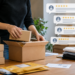 Stock photo of a person packing small boxes into a larger shipping box at a desk with folded clothing and padded envelopes, with four five-star review bubbles overlaid, illustrating e-commerce order fulfillment and customer reviews.