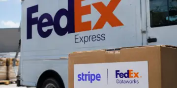 Stock photo of a FedEx Express delivery truck with a cardboard box in the foreground bearing a "Stripe | FedEx Dataworks" label, illustrating a partnership between the two companies.